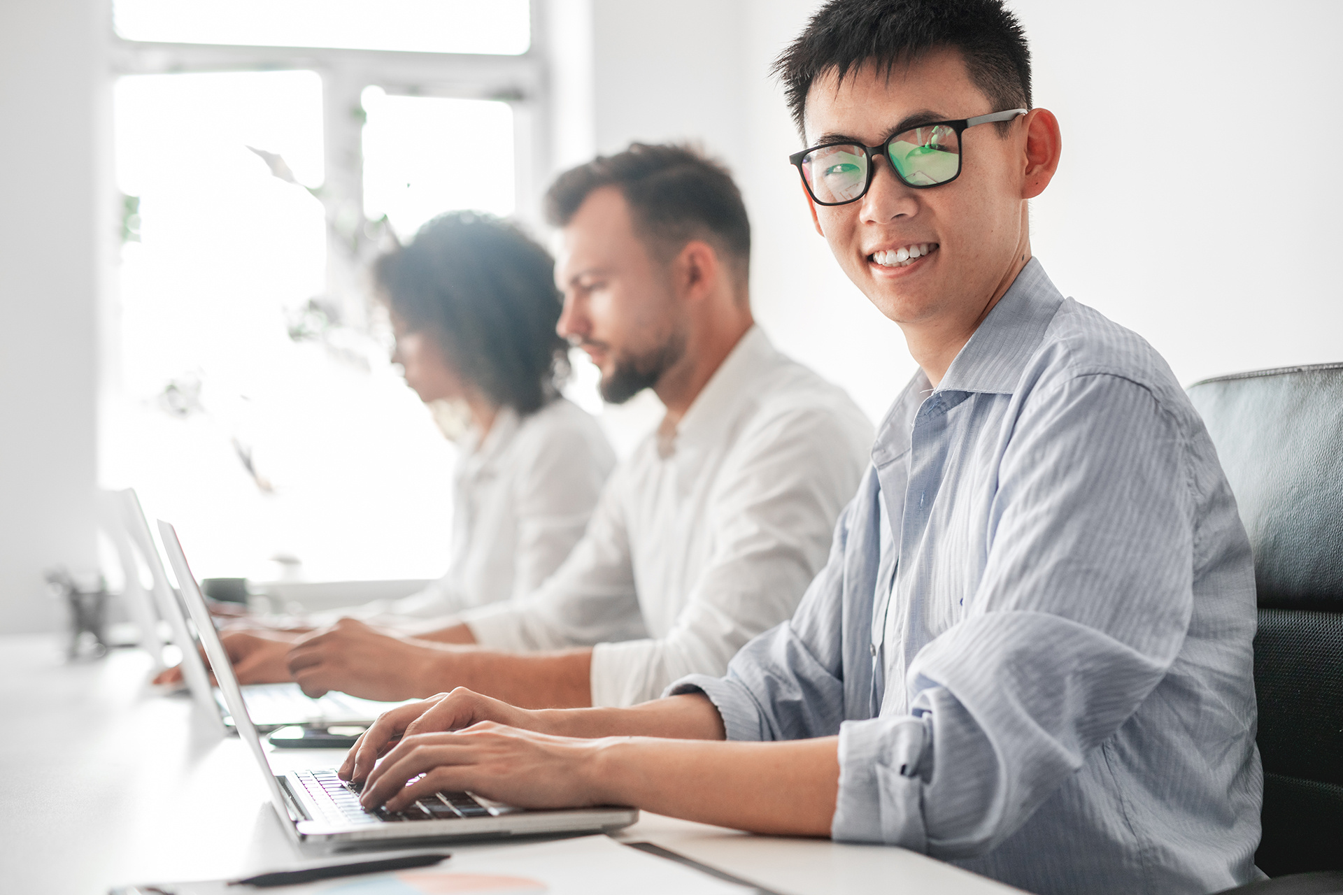 smiling-asian-male-employee-working-on-laptop-near-2022-12-01-18-10-52-utc
